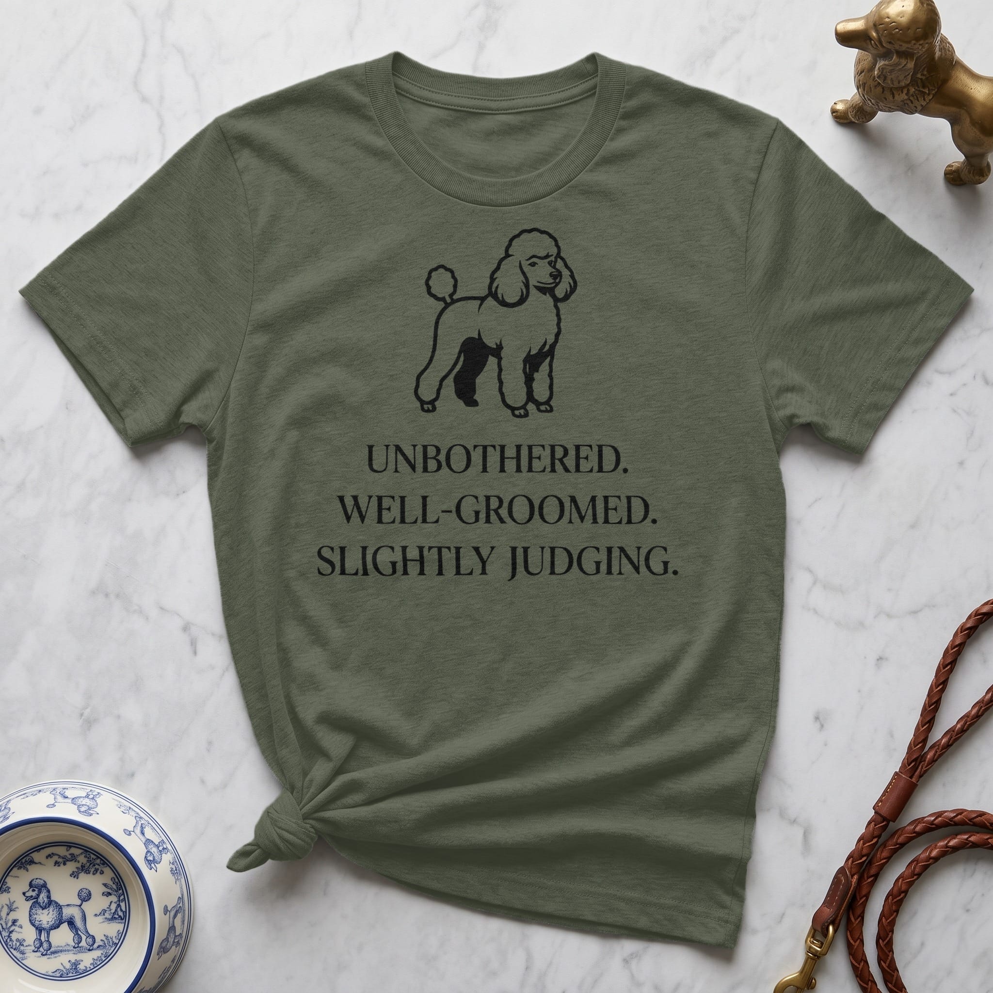 Olive t-shirt with poodle silhouette and text "UNBOTHERED. WELL-GROOMED. SLIGHTLY JUDGING."