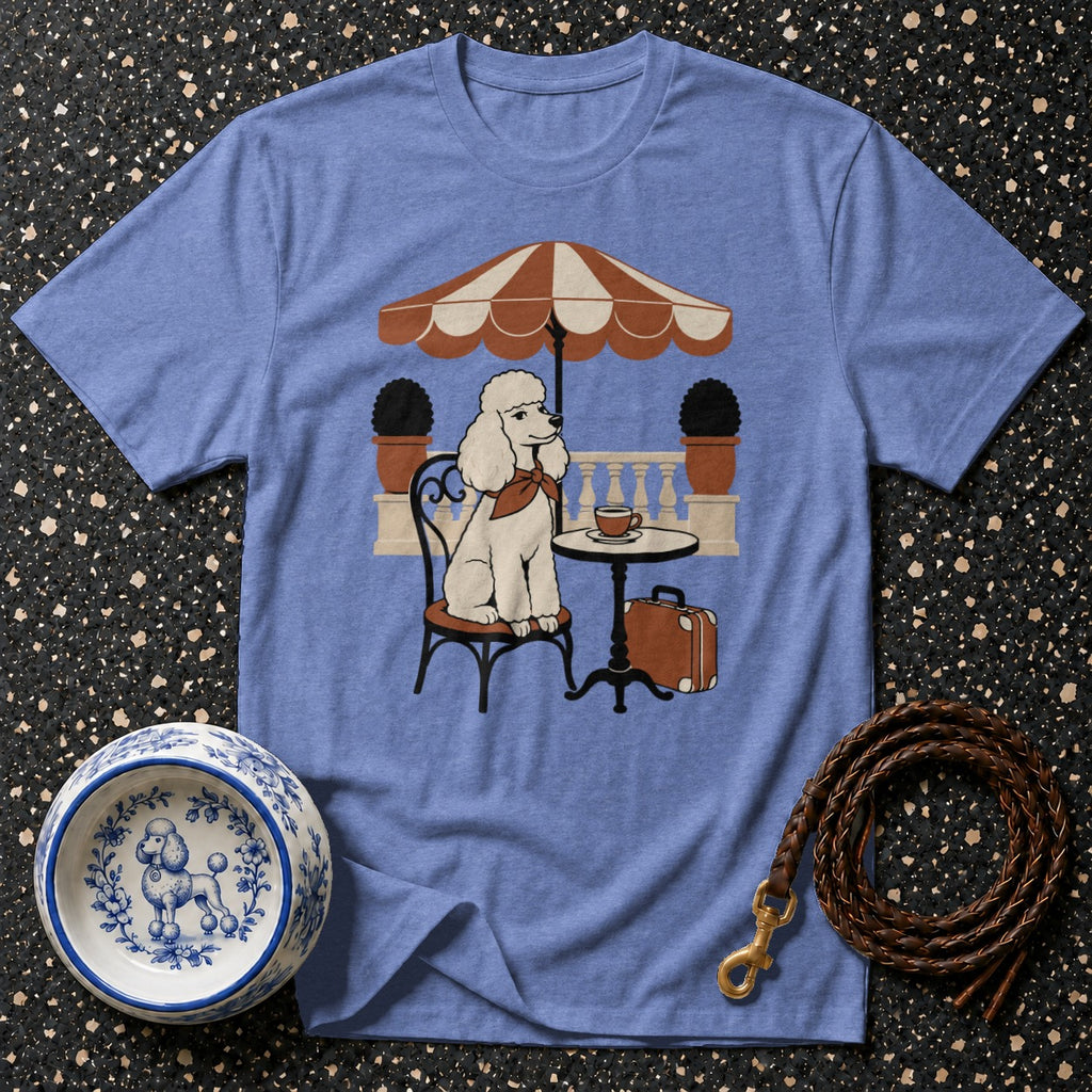 Blue t-shirt with a graphic of a white poodle sitting at a cafe table under an umbrella.