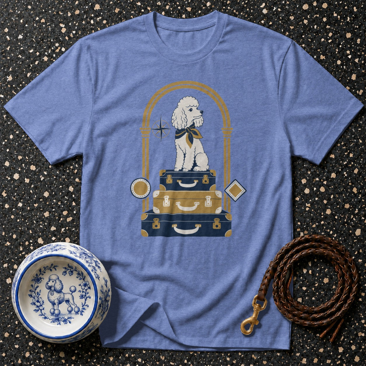 Blue t-shirt with a poodle sitting on stacked suitcases in a golden arch.