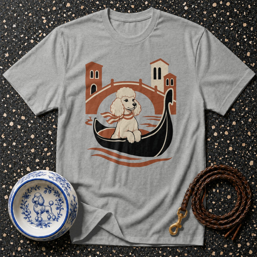 Poodle wearing a scarf in a gondola with Venetian buildings and a bridge.