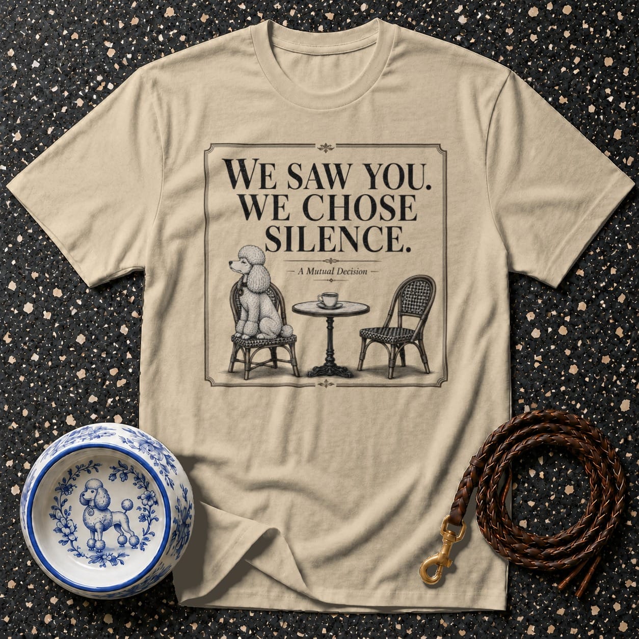 T-shirt with a graphic of a poodle at a table with the text "WE SAW YOU. WE CHOSE SILENCE."