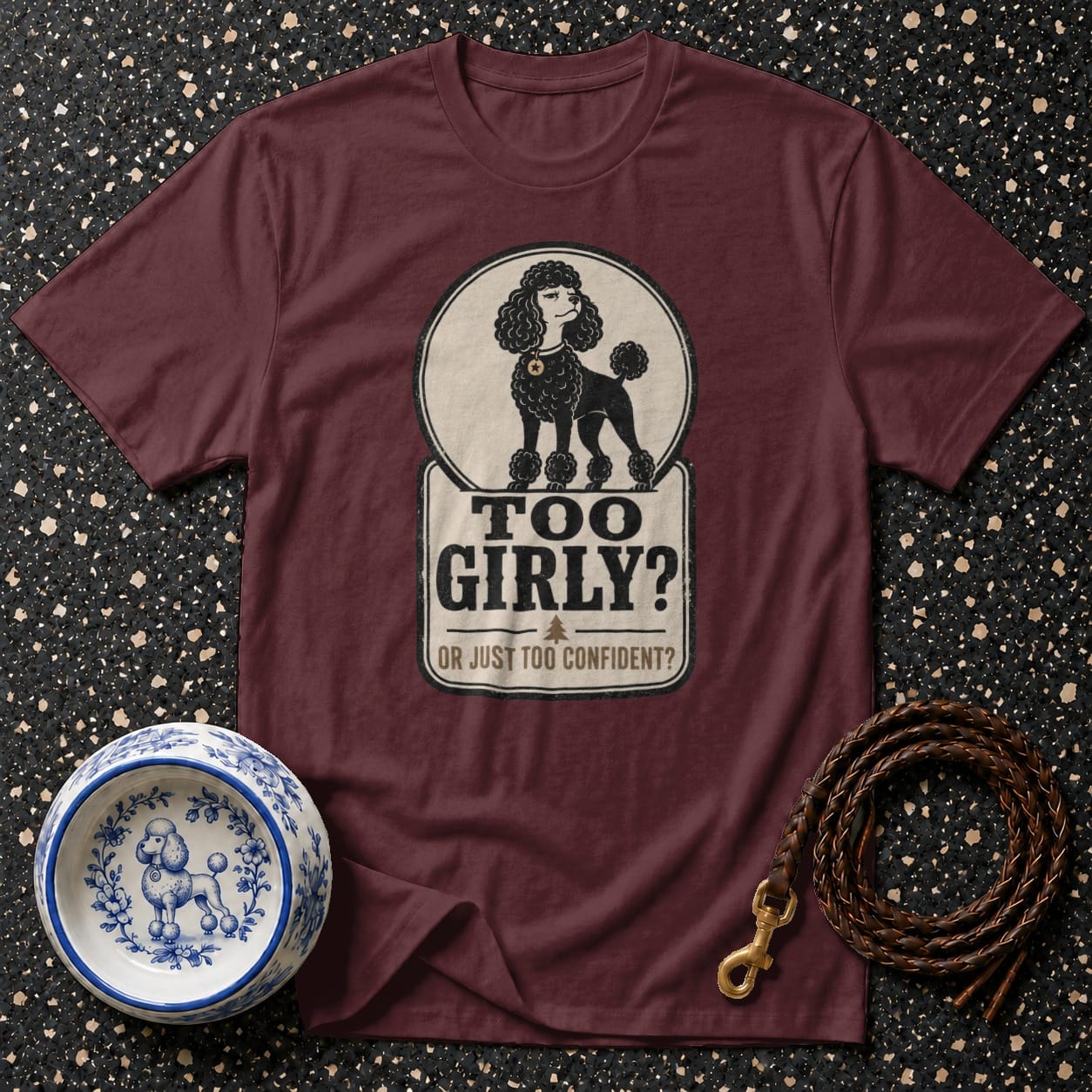 Maroon t-shirt with a poodle graphic and text "TOO GIRLY? OR JUST TOO CONFIDENT?".