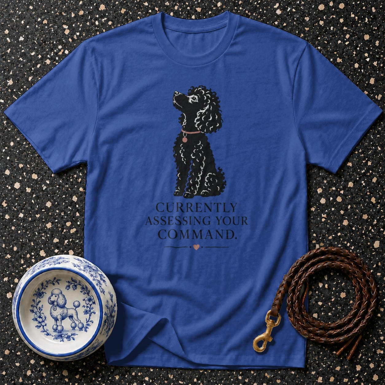 Blue t-shirt with a black poodle graphic and text: "Currently assessing your command."