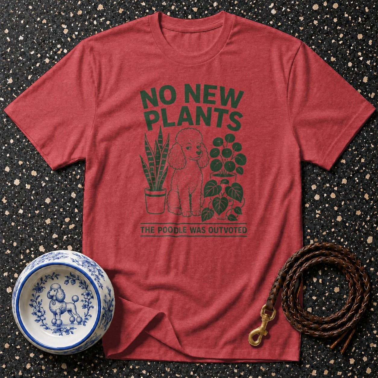 Red t-shirt with green graphic of a poodle and plants, text reads "NO NEW PLANTS THE POODLE WAS OUTVOTED".