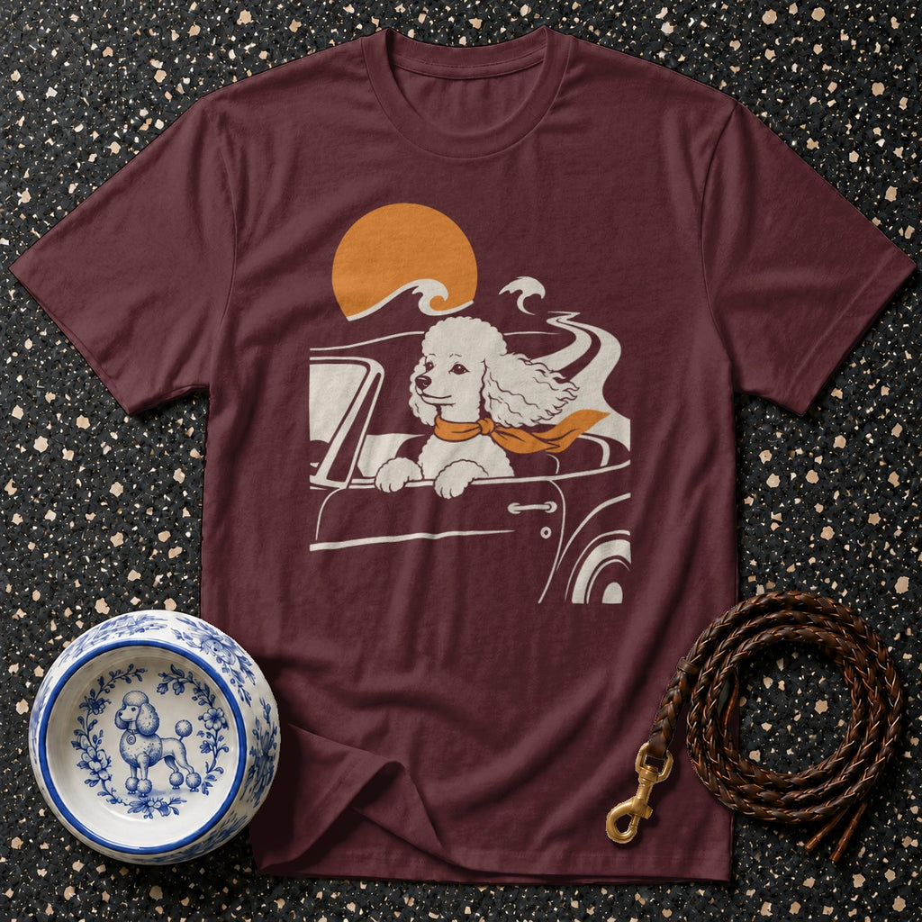 Maroon t-shirt with white poodle driving a convertible with orange scarf and sun.