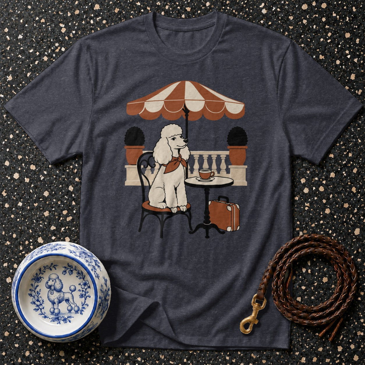 T-shirt with a white poodle sitting at a cafe table under an umbrella.