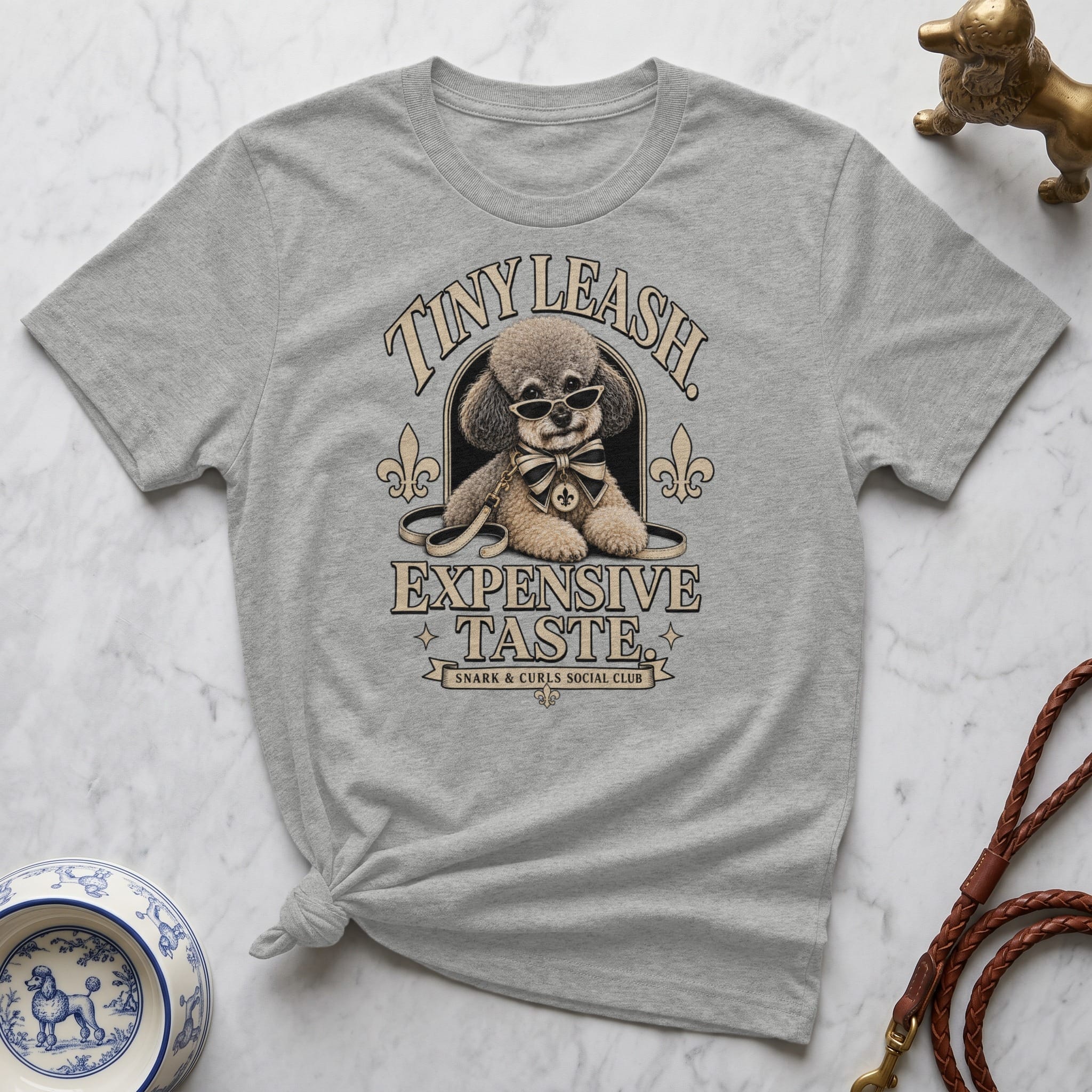 Grey t-shirt with a stylized dog wearing sunglasses and a bowtie, and "TINY LEASH EXPENSIVE TASTE" text.