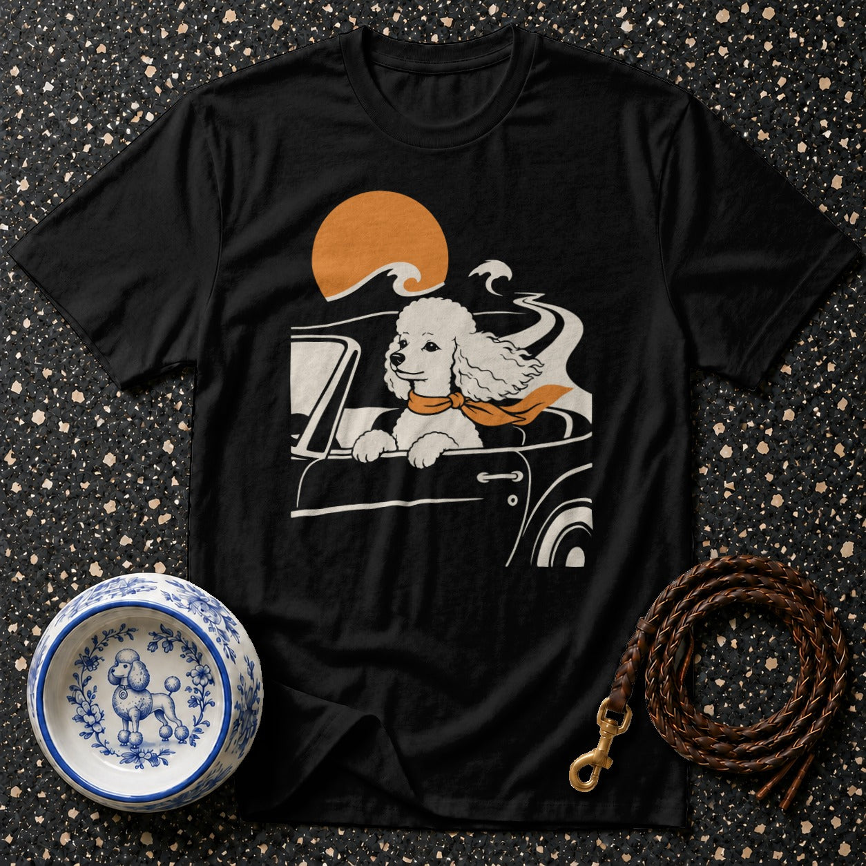 Black t-shirt with poodle driving a car with scarf and orange sun graphic.