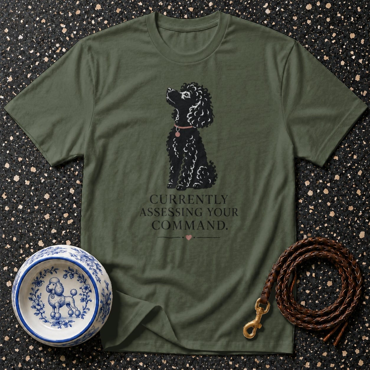 Olive green t-shirt with black poodle graphic and text "Currently Assessing Your Command."