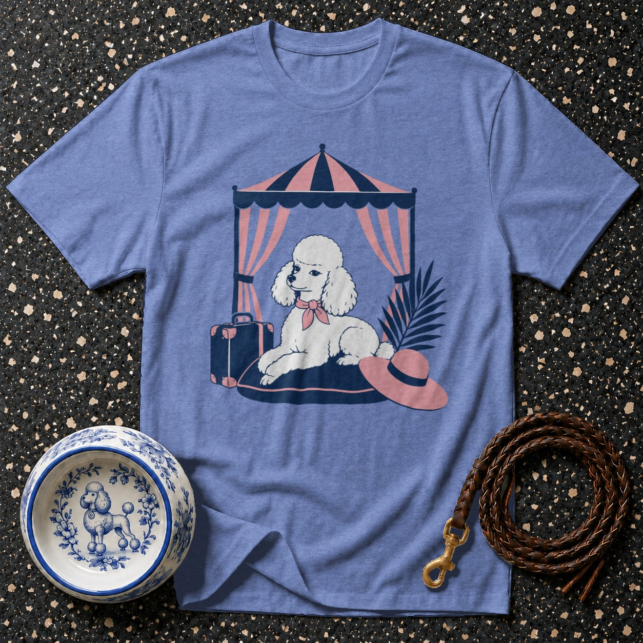 Blue t-shirt with white poodle graphic under a striped tent with a suitcase and hat.