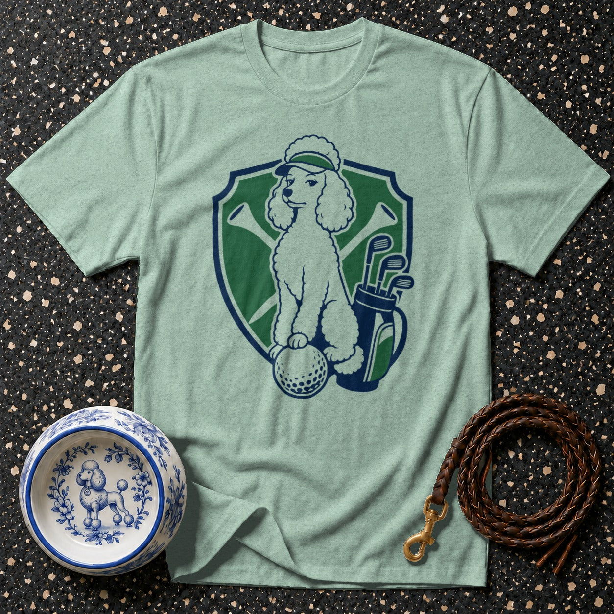 Light green t-shirt with a poodle on a golf ball, golf bag, and clubs emblem.
