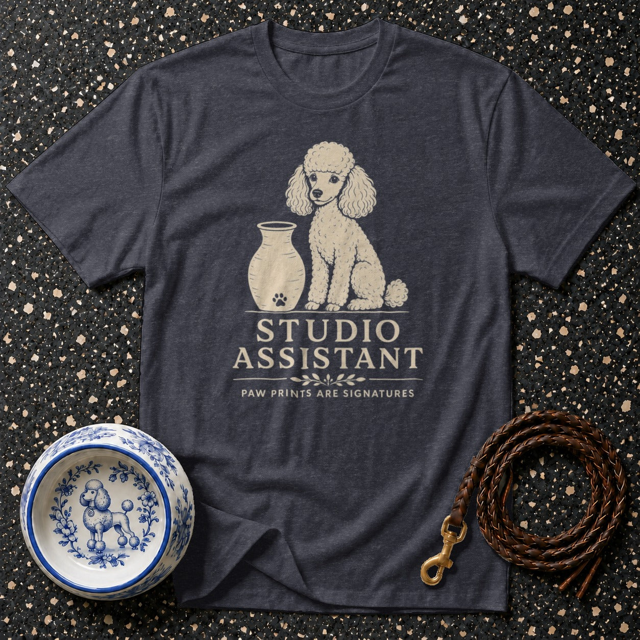 Dark t-shirt with a poodle graphic and "Studio Assistant" text.