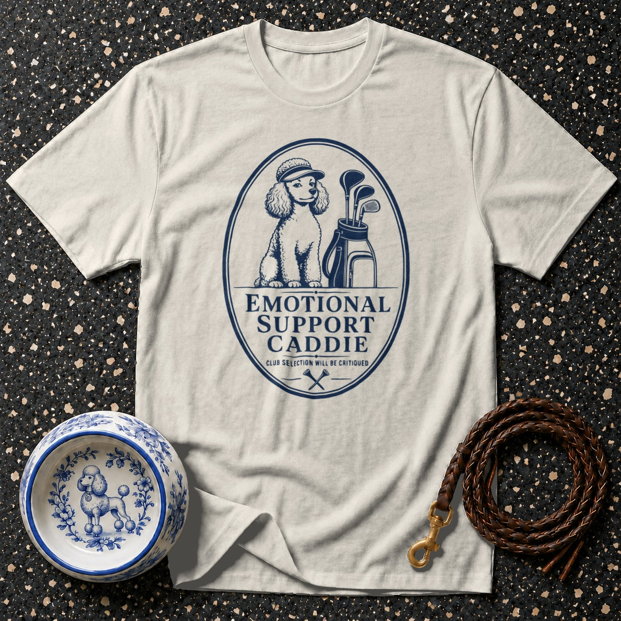 T-shirt with blue graphic of a poodle wearing a golf hat, golf bag, clubs, and text: Emotional Support Caddie.