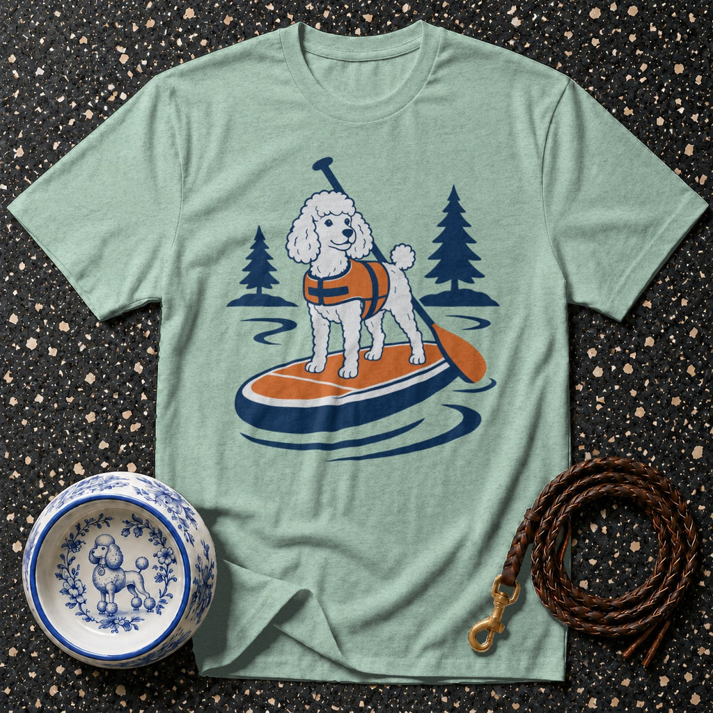 Poodle on paddleboard with paddle and trees graphic on light green t-shirt.