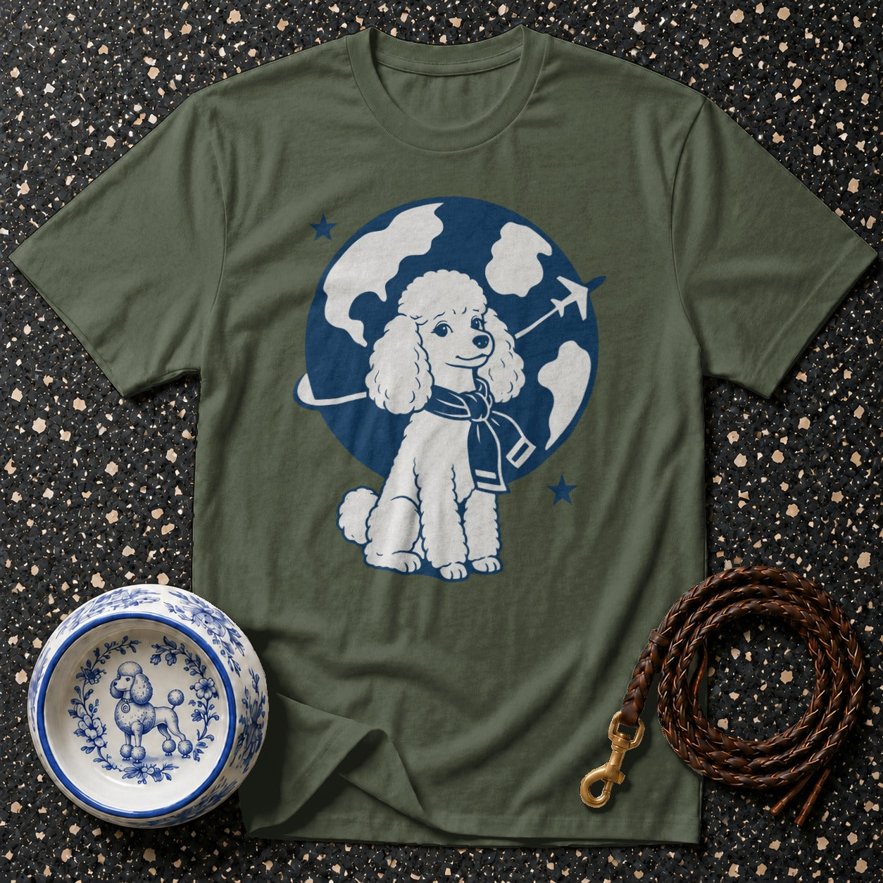 Green t-shirt with graphic of poodle wearing scarf, with globe and airplane behind.