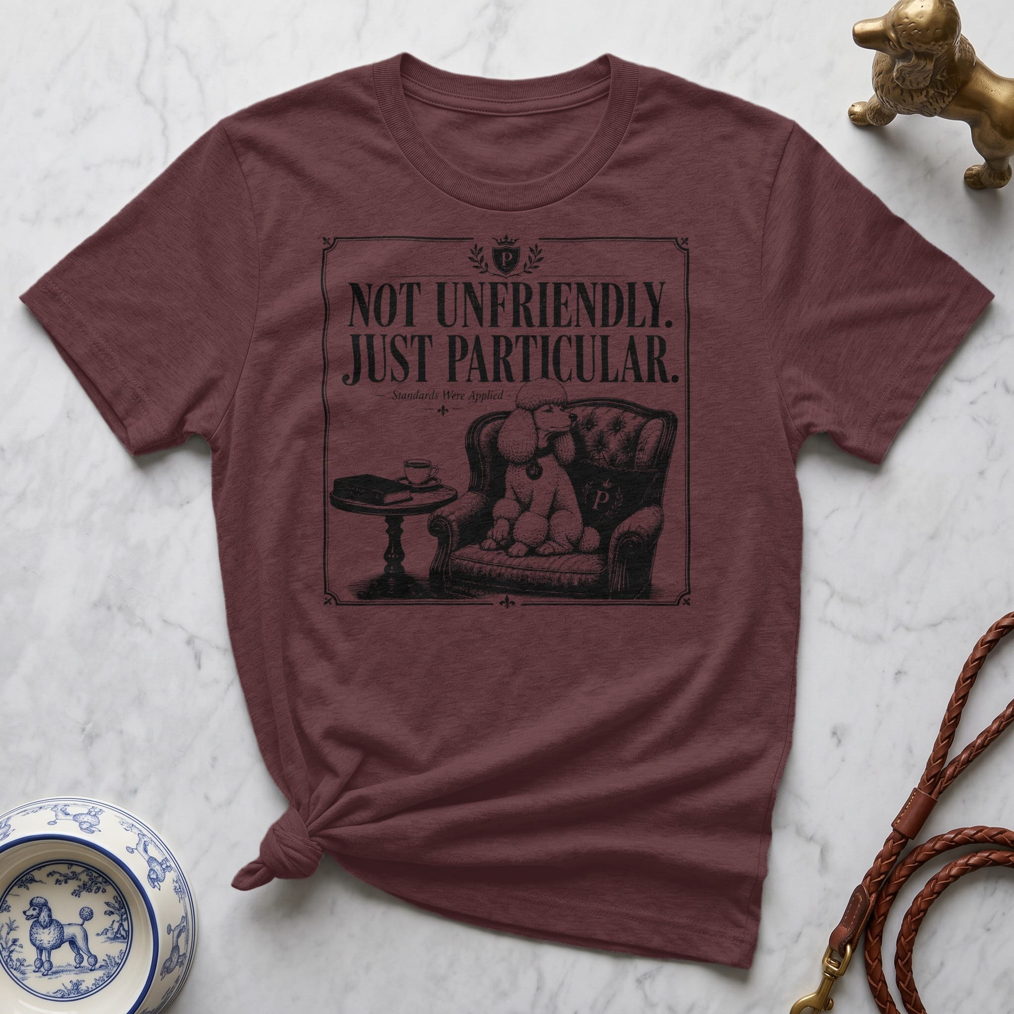 Maroon t-shirt with "Not Unfriendly. Just Particular." text and a poodle illustration.