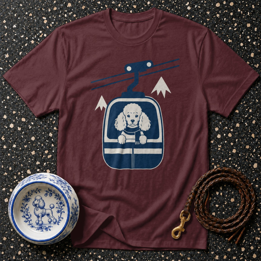 T-shirt with graphic of poodle in ski lift and winter mountain scene.