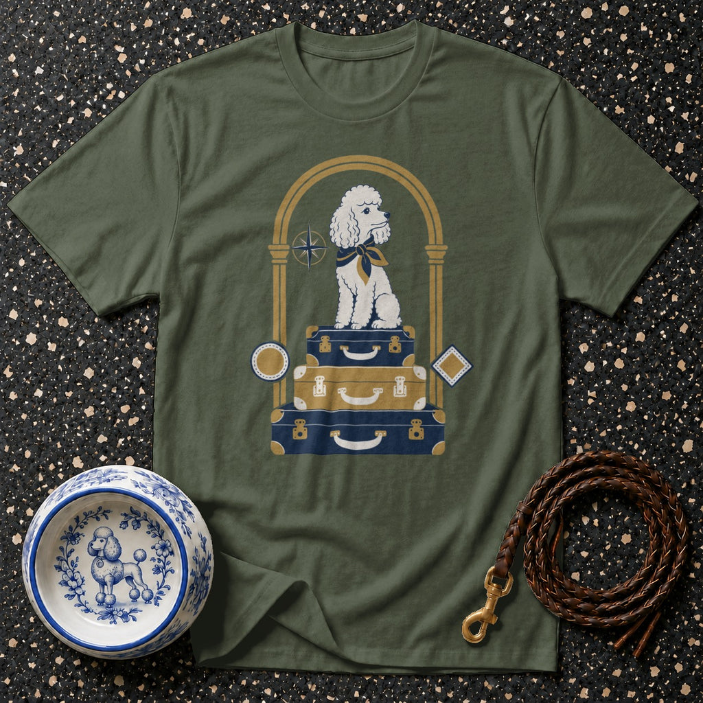 Green t-shirt with a white poodle sitting on stacked luggage.