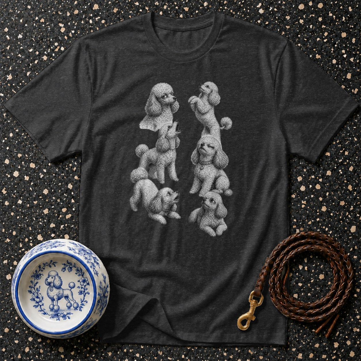 Dark grey t-shirt with six poodles printed in detail, next to a blue and white dog bowl and leather leash.