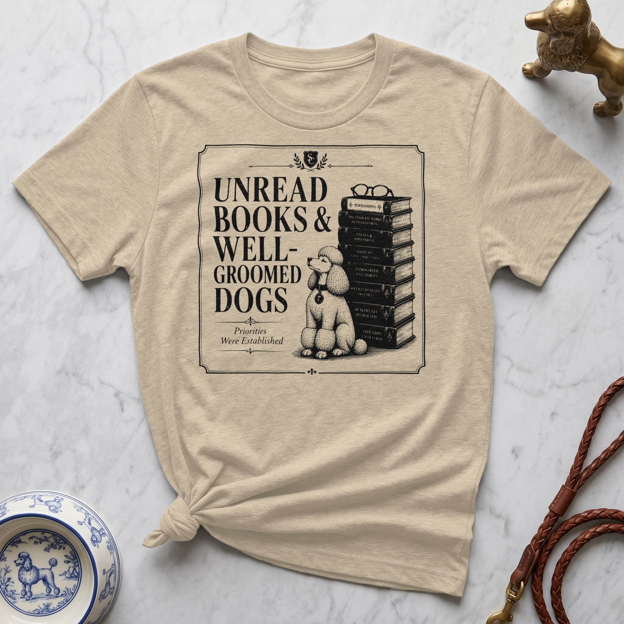 Cream t-shirt with black graphic of poodle and stacked books.