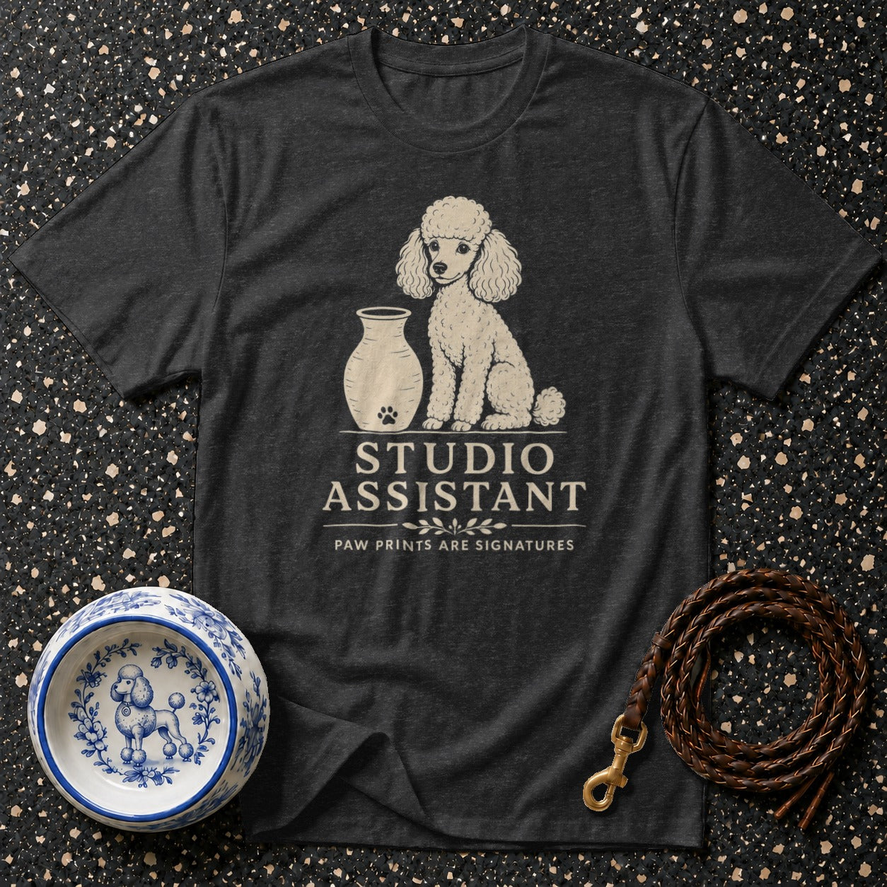Dark t-shirt with white poodle graphic and "STUDIO ASSISTANT" text.