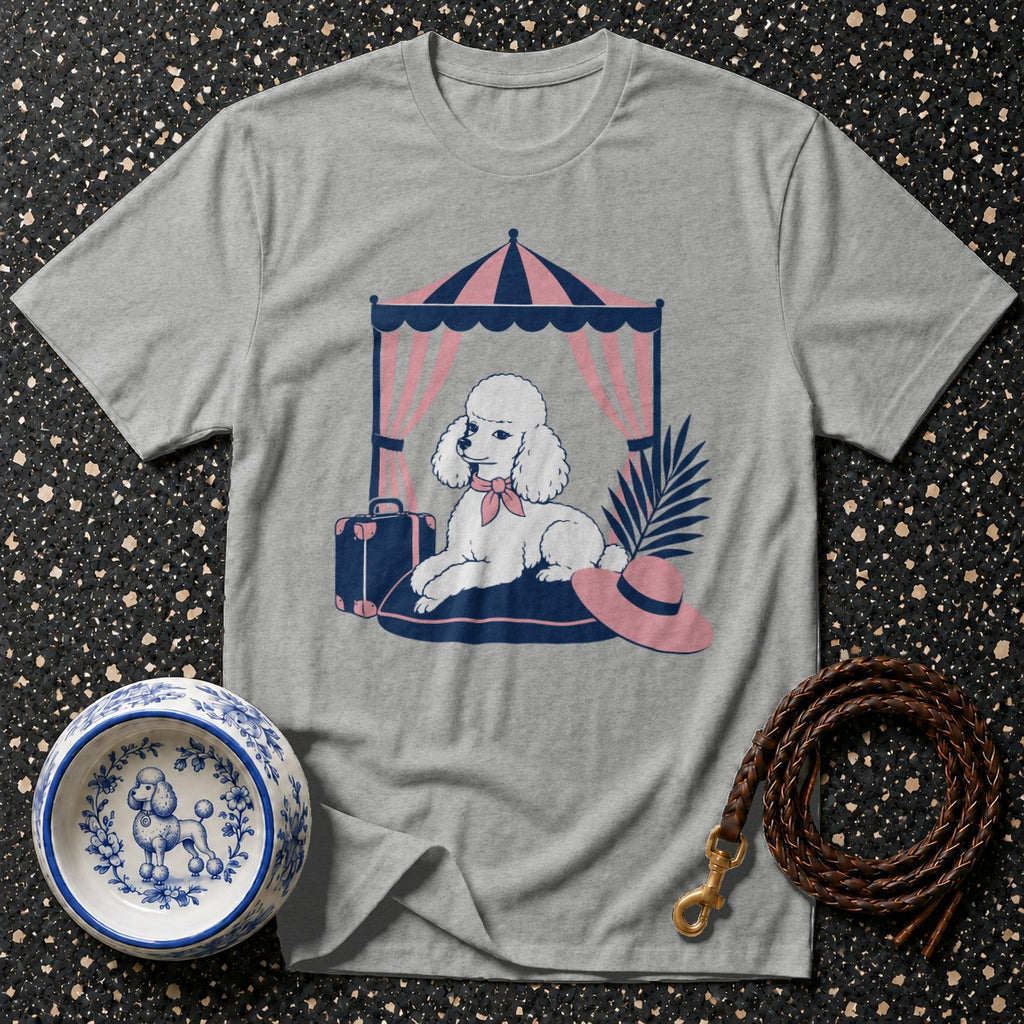 Grey t-shirt with a white poodle graphic lounging under a tent with a suitcase and hat.