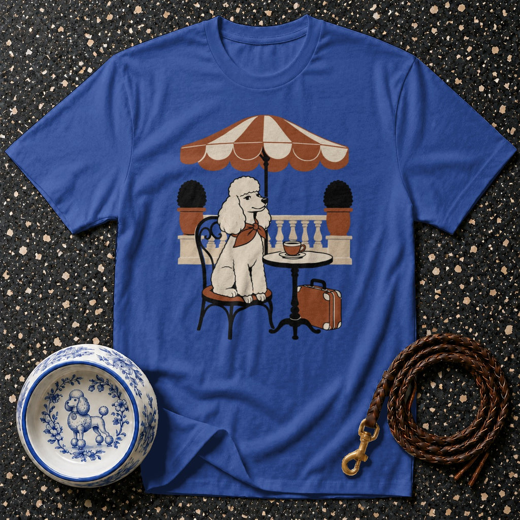 T-shirt with a white poodle sitting at a cafe table under an umbrella.