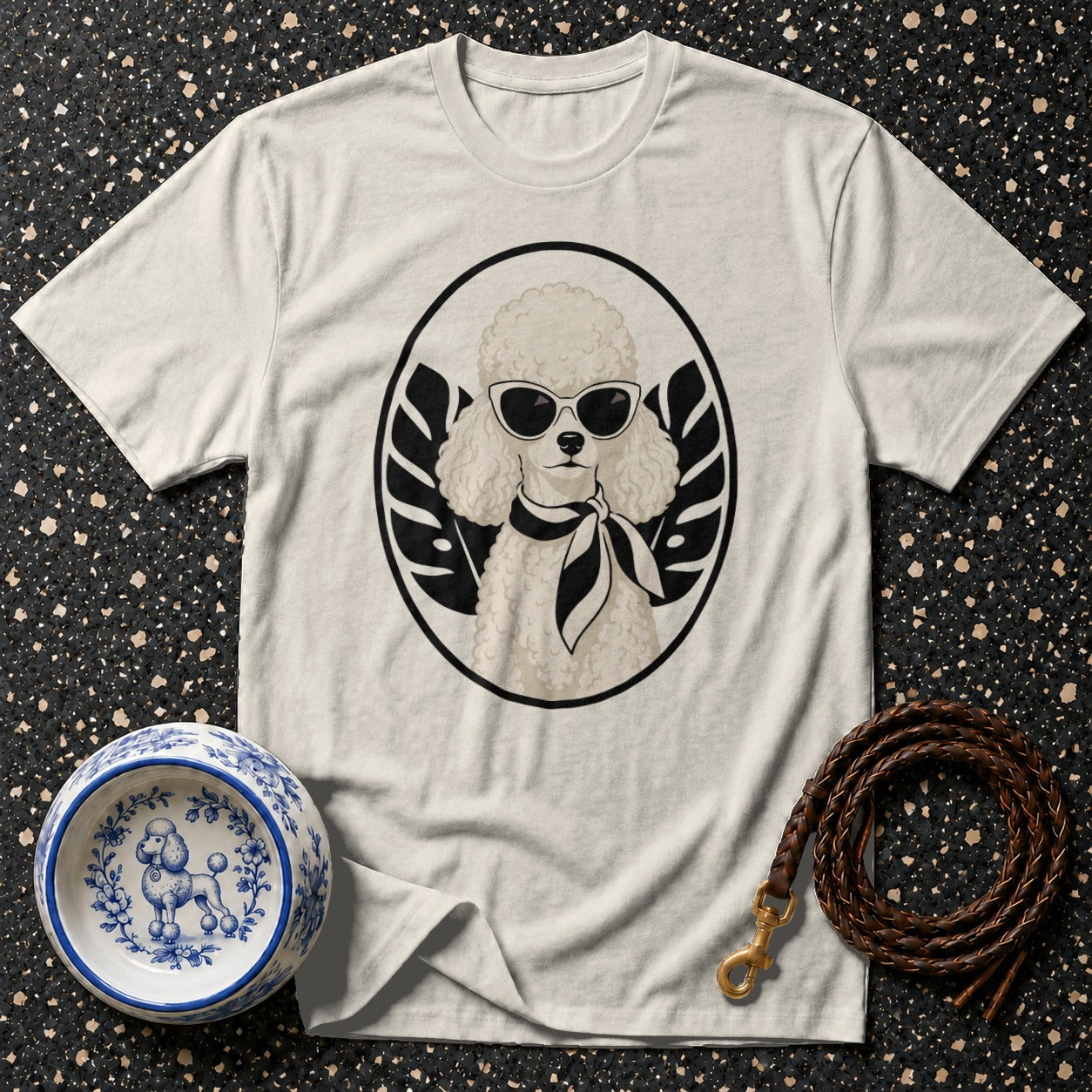T-shirt with a white poodle wearing sunglasses and a scarf, inside a black circle with leaves.