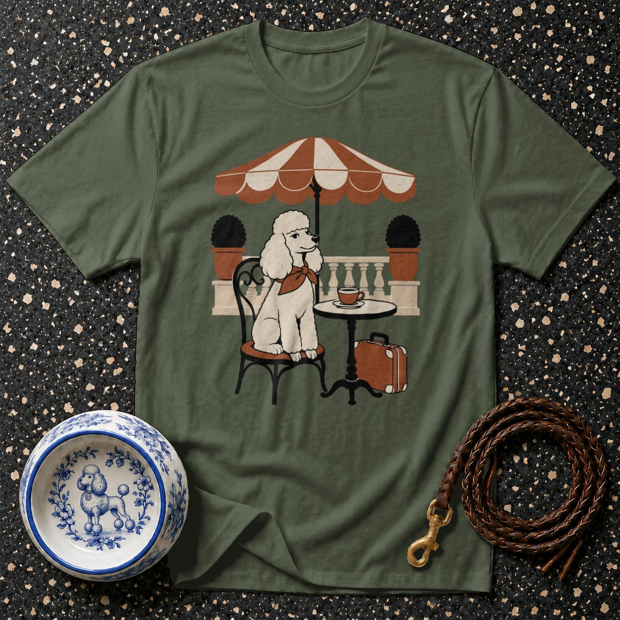 Green t-shirt with a white poodle sitting at a table under an umbrella.