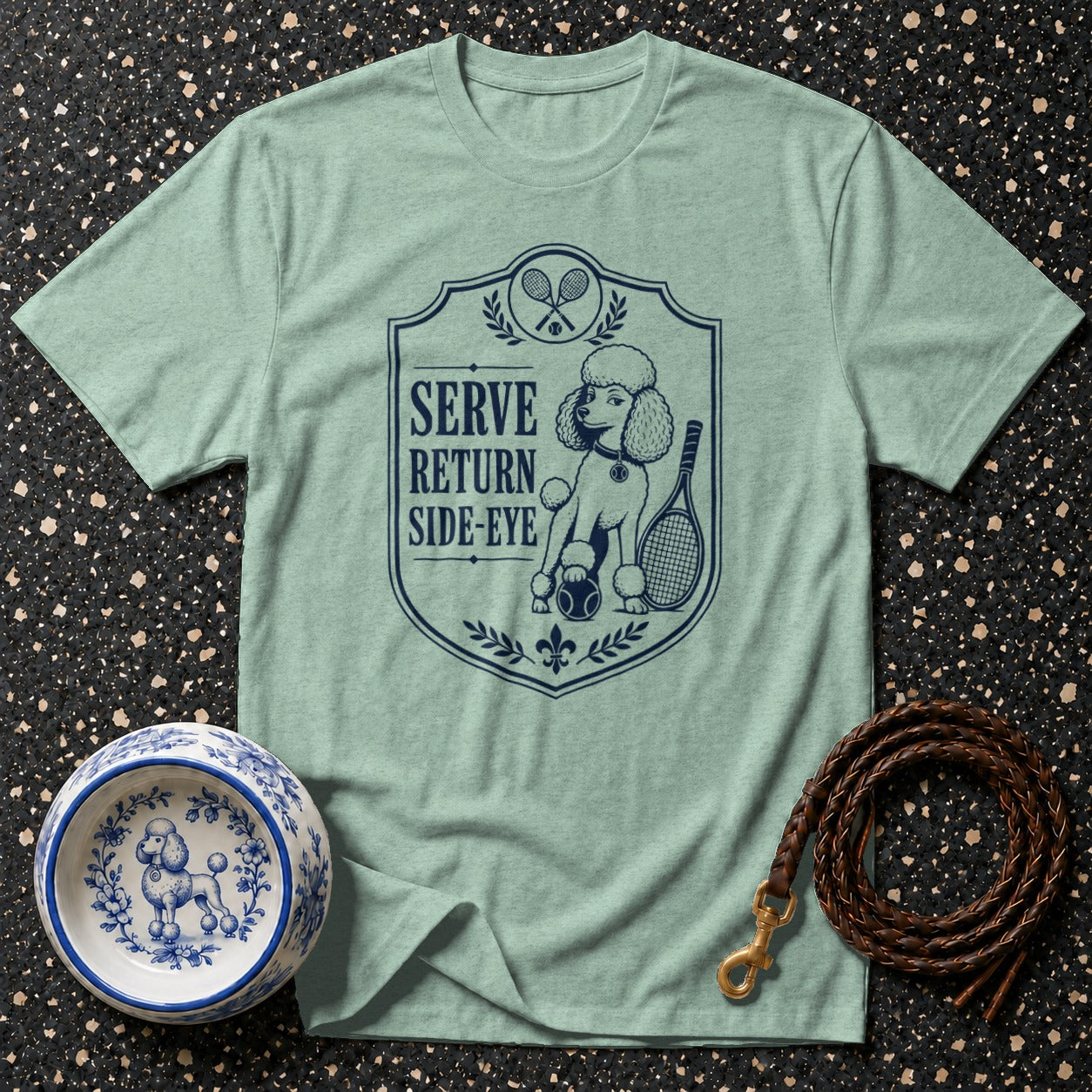 Light green t-shirt with a navy crest depicting a poodle, tennis racquets, and text.