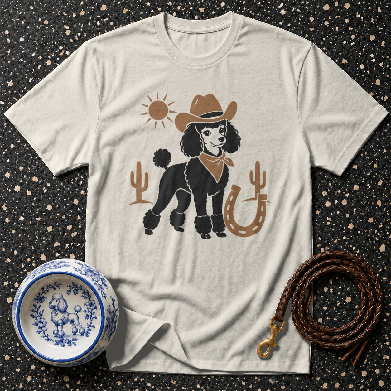 Light-colored t-shirt with a black poodle wearing a cowboy hat and bandana.