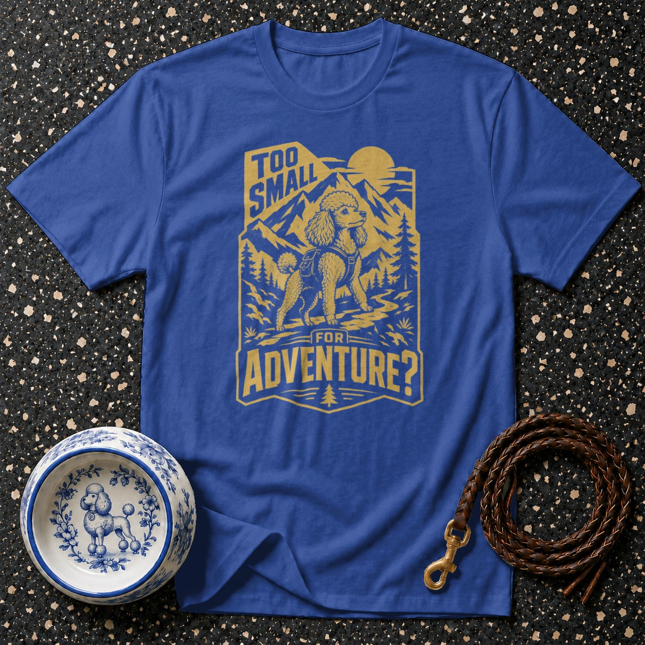 Blue t-shirt with gold graphic of a poodle in the mountains, text reads "Too Small for Adventure?".