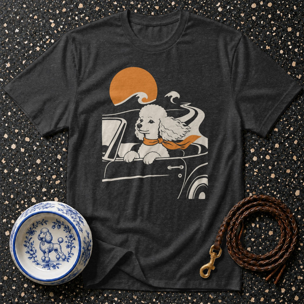 Poodle driving a car with orange scarf and sunset graphic on dark gray t-shirt.