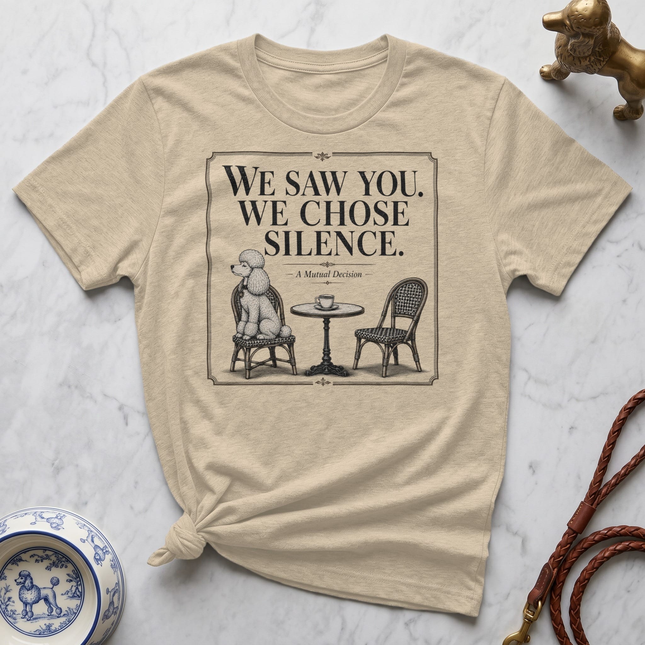 T-shirt with a sketch of a poodle sitting at a table with text "WE SAW YOU. WE CHOSE. SILENCE."